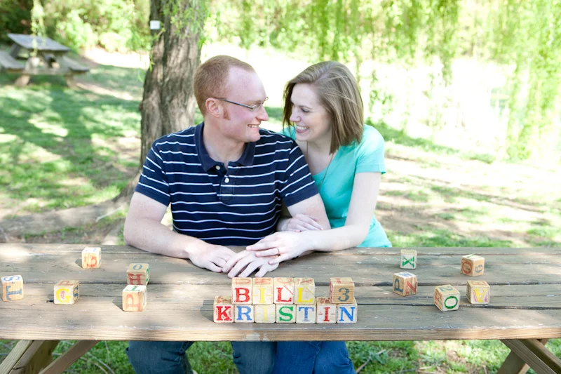 man and woman engagement image at picnic table and blocks