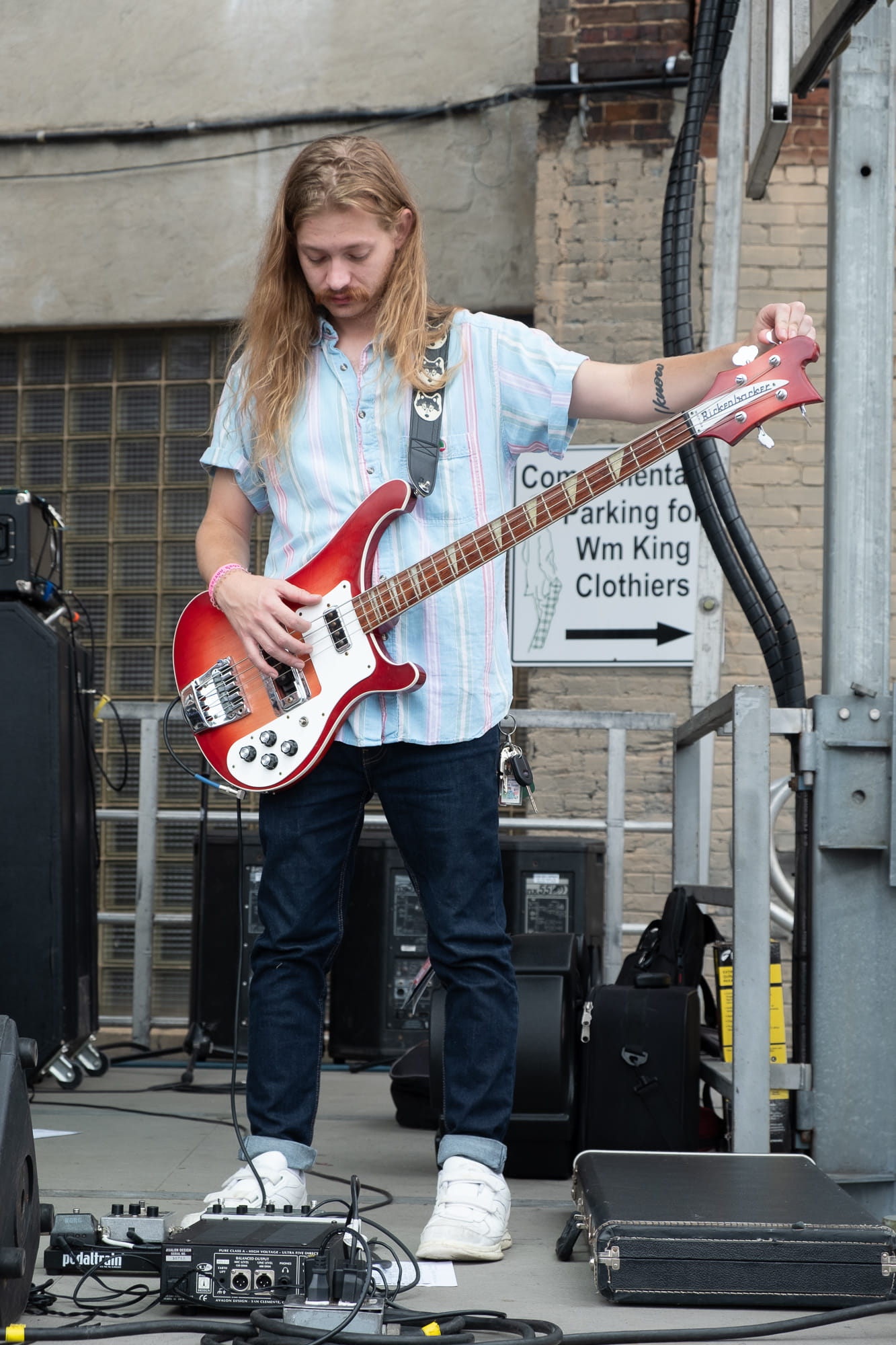 man turning his bass guitar on stage