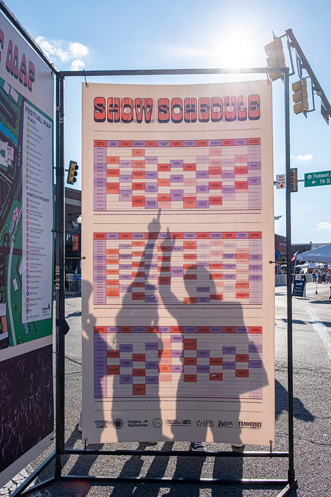 people in shadow looking at music festival schedule