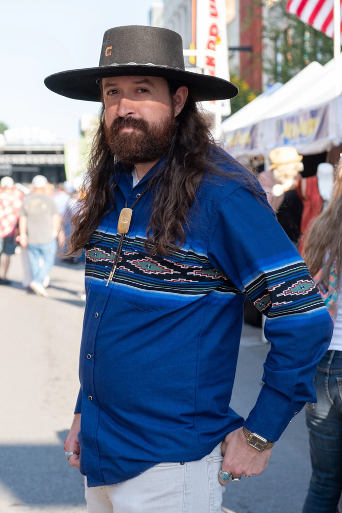 A man in bolo tie and widebrimmed hat on street